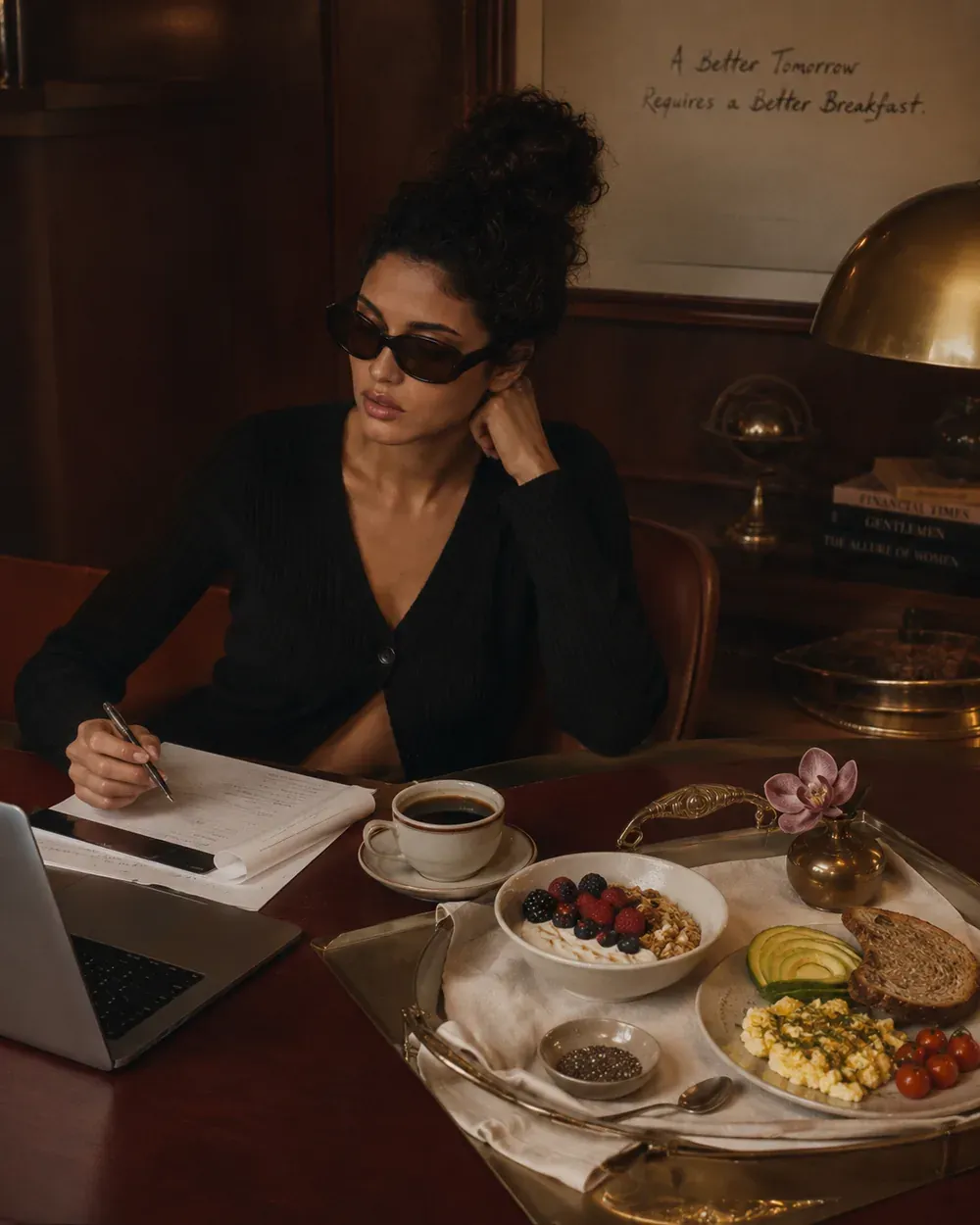 Woman writing beside a high-protein breakfast tray and wall note reading a better tomorrow requires a better breakfast