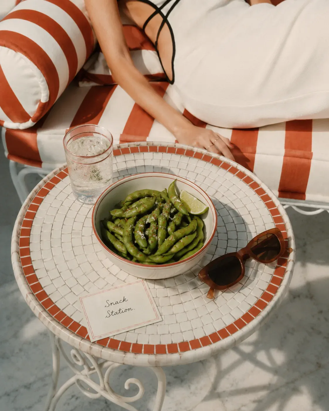 Steamed edamame with sea salt, chili flakes, and lemon on a patterned plate beside a poolside snack note | Becoming Elysian quiet luxury wellness