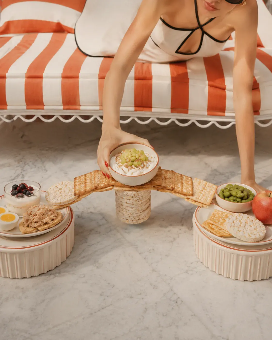 Woman reaching for a balanced protein snack from a calm Mediterranean table, showing snacks as reliable support instead of restriction | Becoming Elysian quiet luxury wellness